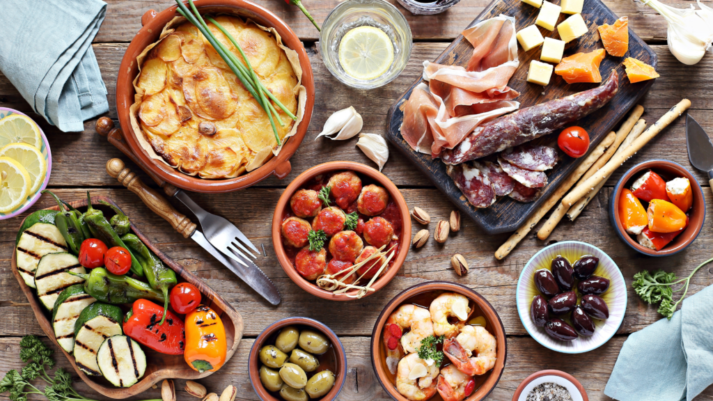 cured meats, roasted vegetables, olives and similar traditiontal spanish foods on a table